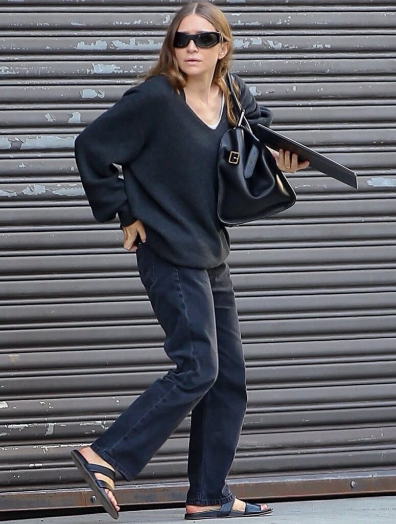 Woman walking in wide-leg black jeans and an oversized dark grey sweater.