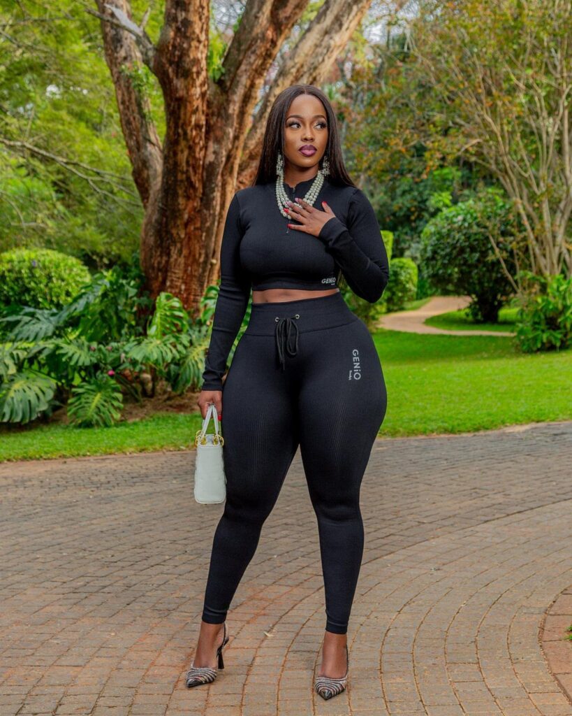 A woman posing in a black long-sleeved crop top and matching black leggings outdoors.